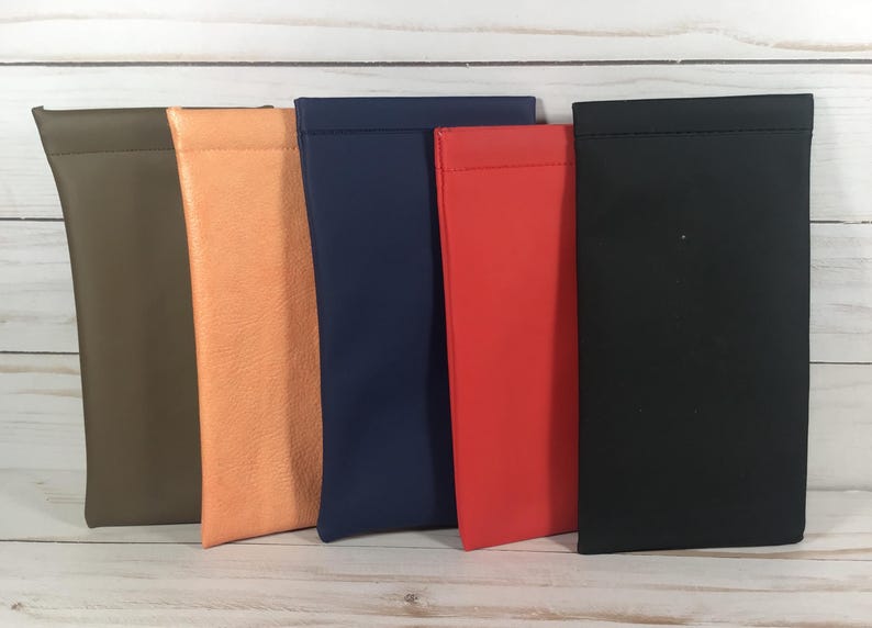 Op de afbeelding: Vijf rechthoekige etuis op een rij, met een gladde, matte afwerking. De kleuren van links naar rechts zijn olijfgroen, licht perzik, marineblauw, felrood en effen zwart. Elk etui heeft een eenvoudig ontwerp met strakke lijnen.