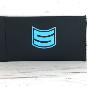 May include: Black rectangular case with a blue logo of a stylized letter "S" inside a curved shape.