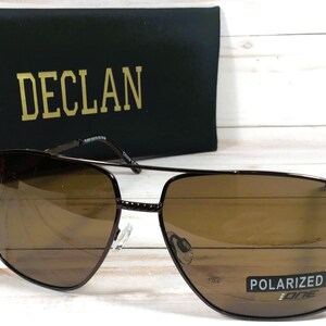 May include: Brown polarized sunglasses with a black frame and the word "DECL&Aacute;N" printed on the case.