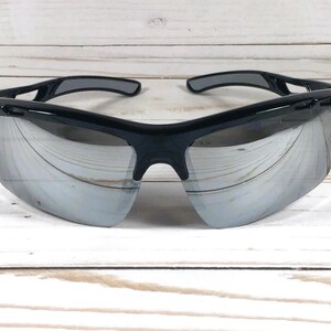 May include: Sport sunglasses featuring a glossy black frame and reflective silver mirrored lenses. The eyewear has a wrap-around design with vented temples and a contoured bridge, providing a wide field of vision and a secure fit for active use.