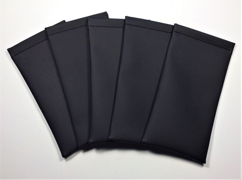 May include: Six black leatherette eyeglass cases arranged in a fan shape. The cases are all closed and have a smooth, matte finish.