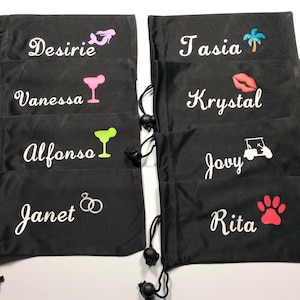 May include: Eight black drawstring bags with white embroidered names and various colored icons. The names are:  Desiree, Vanessa, Alfonso, Janet, Tasia, Krystal, Jovy, and Rita.