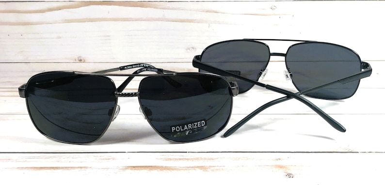 May include: Two pairs of black aviator sunglasses with polarized lenses. The sunglasses have a silver metal frame.