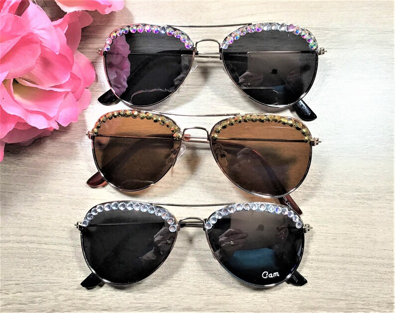Pu&ograve; includere: Tre paia di occhiali da sole aviator con strass intorno alle montature. Gli occhiali hanno lenti di diversi colori: nero, marrone e marrone chiaro.