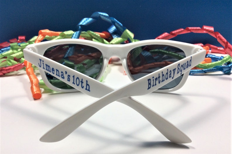 Peut inclure: Lunettes de soleil en plastique blanc avec du texte bleu qui dit "Jimena's 10th Birthday Squad".