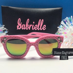 Puede incluir: Gafas de sol rosas con un dise&ntilde;o de estrella en el lateral y lentes de espejo arco&iacute;ris. Las gafas de sol vienen con una funda negra y una etiqueta que dice "Nombre grabado GRATIS".