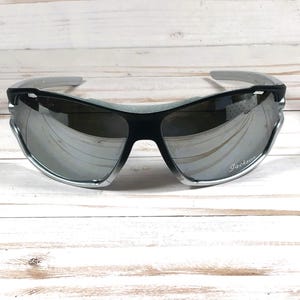 May include: Silver and black sunglasses with mirrored lenses. The sunglasses have a Jackery logo on the right lens.