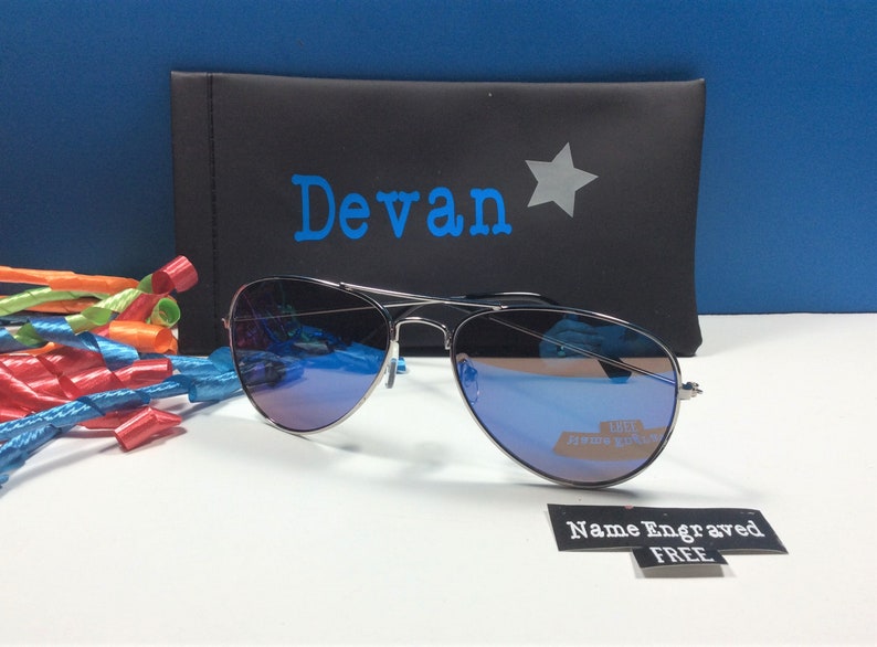 May include: Silver aviator sunglasses with blue mirrored lenses in a black case with the name "Devan" and a star printed on it. The sunglasses come with a free name engraved tag.