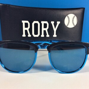 May include: Blue mirrored sunglasses with black frames and a black case with the word "RORY" and a baseball graphic.