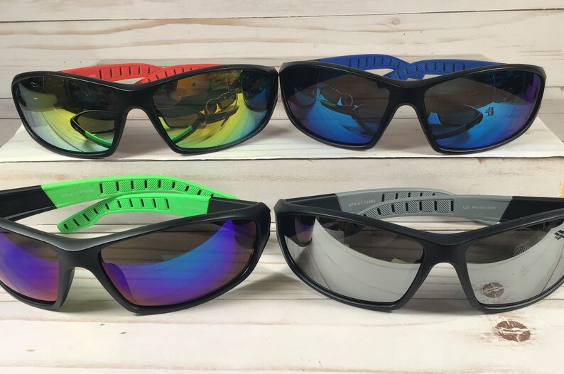 May include: Four pairs of black sunglasses with different colored lenses and frames. The lenses are mirrored and the frames have a rubberized texture. The sunglasses are arranged in two rows of two.