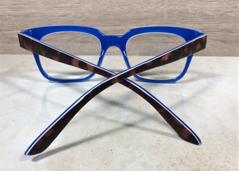 May include: Blue eyeglasses with a tortoiseshell pattern on the temples. The frames are a vibrant blue, and the arms feature a brown and black tortoiseshell design with a white stripe. The glasses are designed for vision correction.