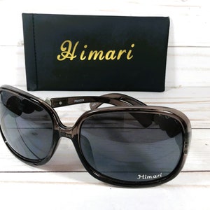 Puede incluir: Gafas de sol de pl&aacute;stico marr&oacute;n con lentes oscuros. Las gafas tienen la palabra "Himari" impresa en la lente derecha y la caja tiene la palabra "Himari" impresa en la parte delantera.