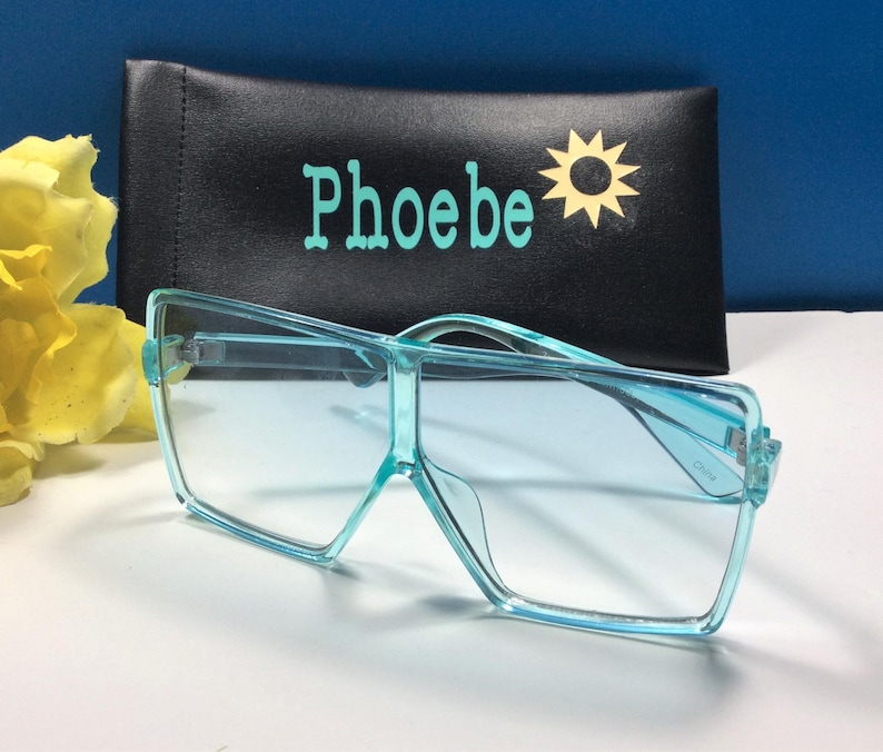 May include: Light blue square-shaped sunglasses with a black case that says "Phoebe" and has a yellow sun graphic.