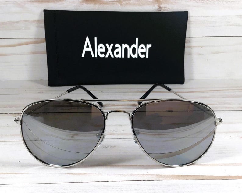 May include: Silver aviator sunglasses with mirrored lenses and a black case with the word "Alexander" printed on it.