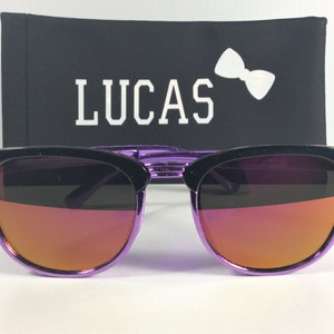 May include: Purple and black sunglasses with a mirrored lens. The sunglasses are in a black case with the word "LUCAS" printed in white.