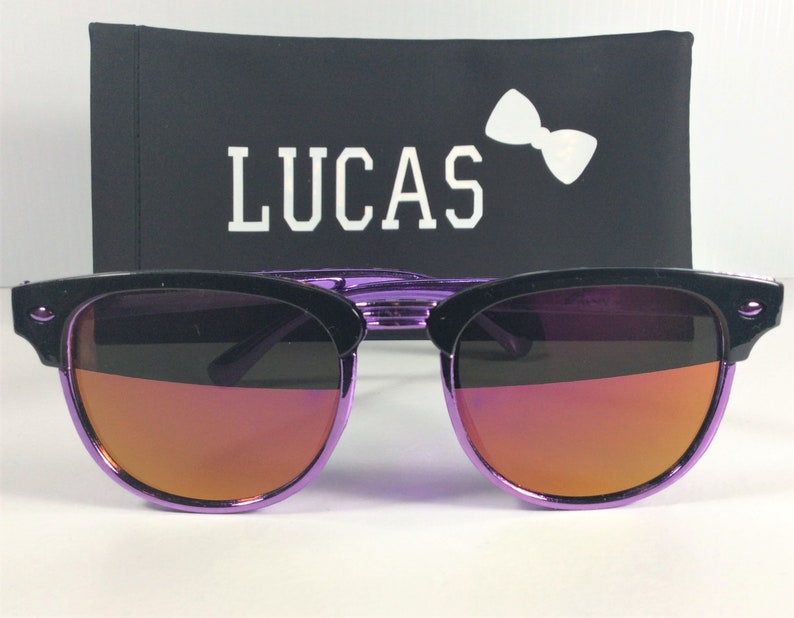 May include: Purple and black sunglasses with a mirrored lens. The sunglasses are in a black case with the word "LUCAS" printed in white.