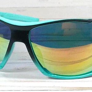May include: A pair of black and turquoise sunglasses with a mirrored lens. The sunglasses have a sporty design and are ideal for outdoor activities.