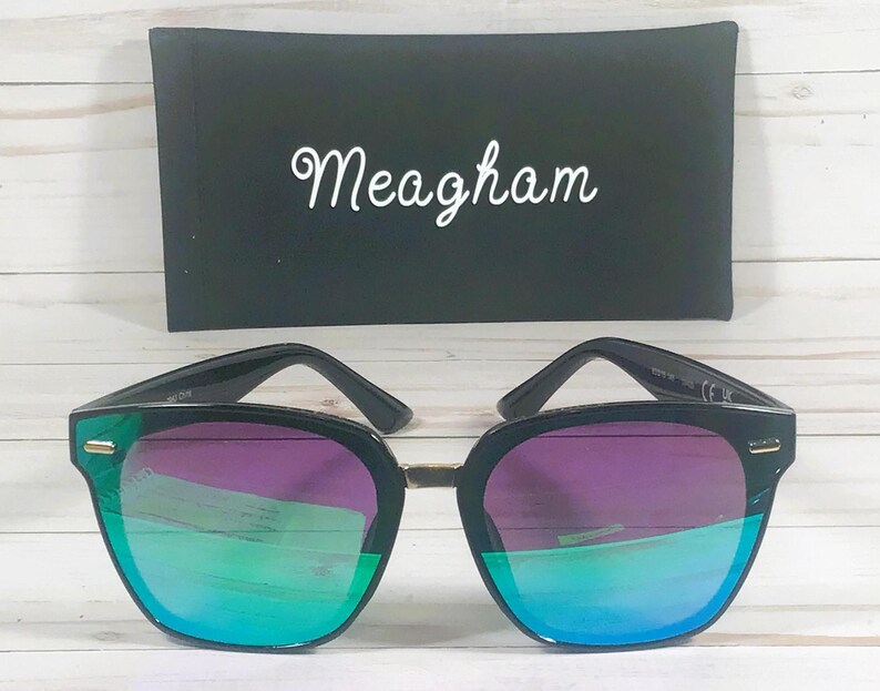 May include: Black sunglasses with a green and purple mirrored lens. The sunglasses have a gold accent on the frame.