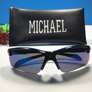 May include: Black sunglasses with blue tinted lenses and a black case with the word "MICHAEL" printed on it.