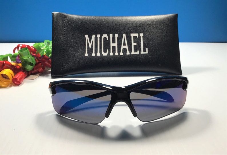 May include: Black sunglasses with blue tinted lenses and a black case with the word "MICHAEL" printed on it.