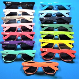 Op de afbeelding: Een set van 15 paar zonnebrillen in verschillende kleuren, waaronder zwart, wit, zilver, roze, roze, paars, teal, oranje, geel, rood, blauw, babyblauw, marine, groen en limoengroen. Elk paar heeft een anders gekleurd montuur en zwarte glazen.