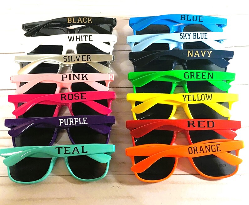 K&ouml;nnte beinhalten: Eine Sammlung von Sonnenbrillen in verschiedenen Farben, darunter Schwarz, Wei&szlig;, Silber, Rosa, Rose, Lila, T&uuml;rkis, Blau, Himmelblau, Marine, Gr&uuml;n, Gelb, Rot und Orange. Jede Brille hat einen farblich passenden Rahmen mit dem aufgedruckten Farbnamen.
