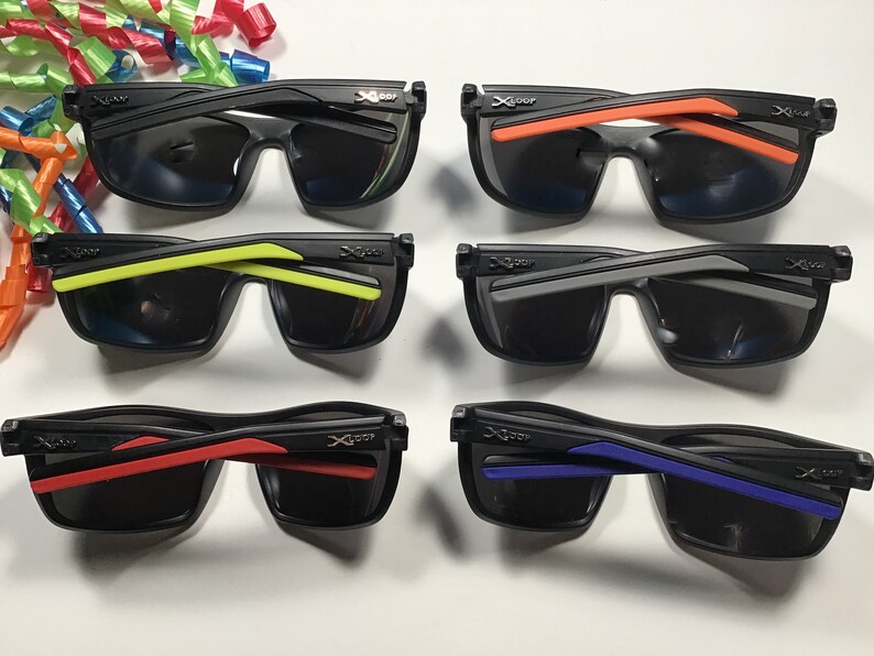 Peut inclure: Six paires de lunettes de soleil noires avec des verres fonc&eacute;s et des accents color&eacute;s sur les branches. Les branches pr&eacute;sentent des couleurs orange, jaune, grise, rouge et bleue. Les lunettes sont dispos&eacute;es en deux rang&eacute;es de trois.