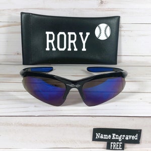 May include: Black sunglasses with blue mirrored lenses and a black case with the name "RORY" and a baseball graphic.