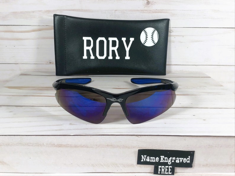 May include: Black sunglasses with blue mirrored lenses and a black case with the name "RORY" and a baseball graphic.