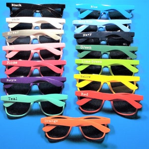 May include: A set of 15 pairs of sunglasses in various colors, including black, white, silver, pink, rose, purple, teal, orange, yellow, red, blue, baby blue, navy, green, and lime green. Each pair has a different color frame and black lenses.