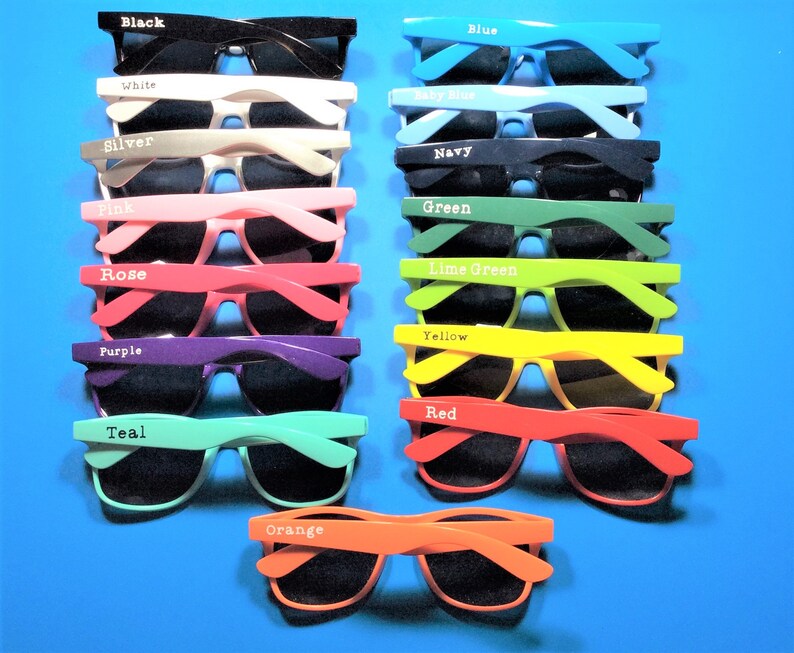 May include: A set of 15 pairs of sunglasses in various colors, including black, white, silver, pink, rose, purple, teal, orange, yellow, red, blue, baby blue, navy, green, and lime green. Each pair has a different color frame and black lenses.