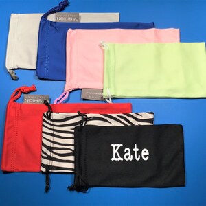 May include: Assortment of 10 eyeglass cleaning cloths in various colors and patterns, including red, white, black, blue, pink, green, and zebra print. Some cloths have the word "FASHION" printed on them, and one cloth has the name "Kate" printed on it.