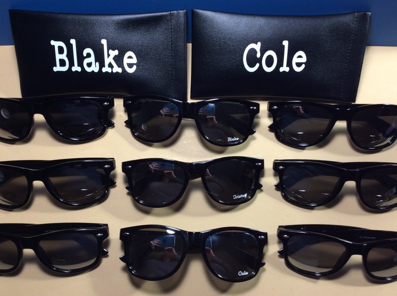 May include: Eight pairs of black sunglasses with the names "Blake" and "Cole" printed on the lenses. The sunglasses are displayed in rows of two, with each row alternating between the two names.