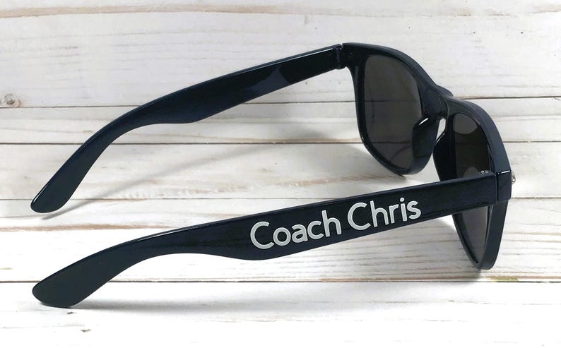 May include: Black sunglasses with the text "Coach Chris" printed on the side.
