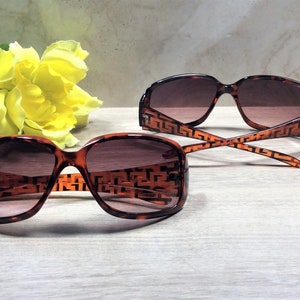 Peut inclure: Deux paires de lunettes de soleil en &eacute;caille de tortue marron avec un motif g&eacute;om&eacute;trique sur les montures. Les lunettes de soleil ont des verres marrons.
