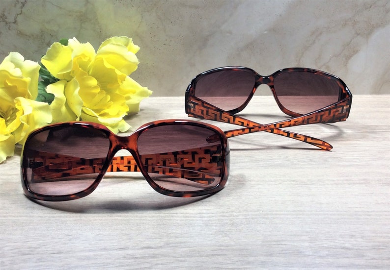 Peut inclure: Deux paires de lunettes de soleil en &eacute;caille de tortue marron avec un motif g&eacute;om&eacute;trique sur les montures. Les lunettes de soleil ont des verres marrons.