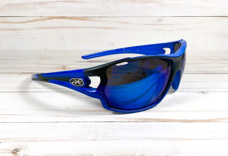 May include: Blue and black wraparound sunglasses with blue mirrored lenses. The sunglasses have a logo on the side.
