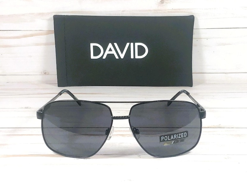 May include: Black aviator sunglasses with a black frame and dark gray lenses. The sunglasses have the word "DAVID" printed on the case and "POLARIZED" printed on the lenses.