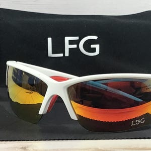 May include: White sunglasses with reflective orange and yellow lenses featuring the text LFG on the bottom right lens. The sunglasses are accompanied by a black drawstring pouch with the white text LFG printed on the front surface.