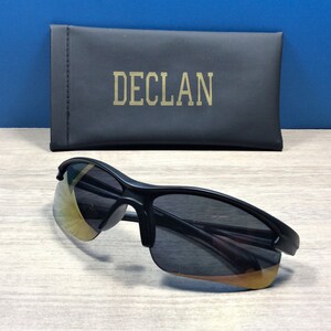 May include: Black sunglasses with a gold-tinted lens and a black case with the word "DECL&Aacute;N" printed on it.