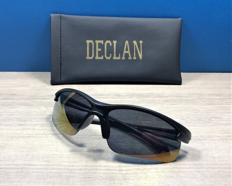 May include: Black sunglasses with a gold-tinted lens and a black case with the word "DECL&Aacute;N" printed on it.