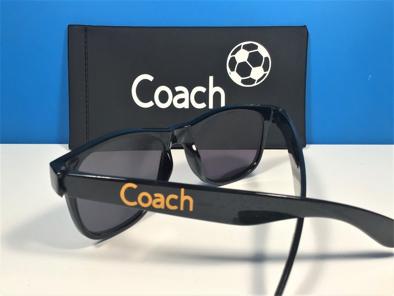 May include: Black sunglasses with a Coach logo on the side and a black case with a soccer ball and the word "Coach" on it.