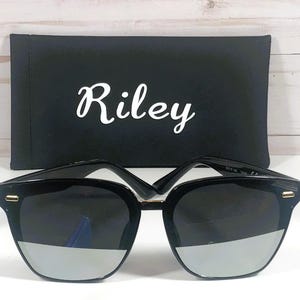 May include: Black sunglasses with a silver mirrored lens and a black case with the word "Riley" printed on it.