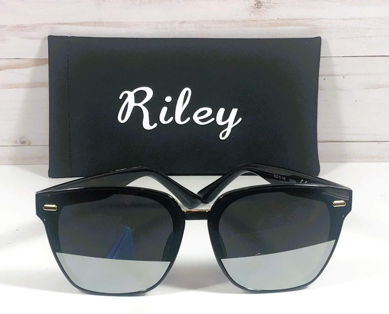 May include: Black sunglasses with a silver mirrored lens and a black case with the word "Riley" printed on it.