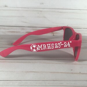 May include: Pink sunglasses with a white soccer ball and the text "MRHS 23-24" on the side.