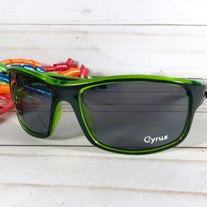 K&ouml;nnte beinhalten: Gr&uuml;ne Sonnenbrille mit dunklen Gl&auml;sern und dem Wort "Cyrus" auf dem rechten Glas.