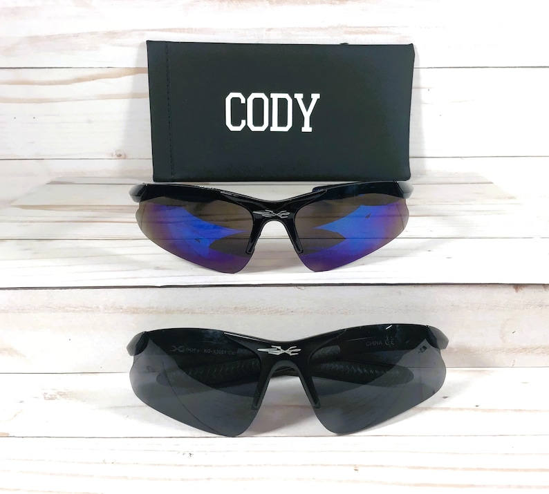 May include: Black sunglasses with a blue mirrored lens and a black case with the name "CODY" printed on it.