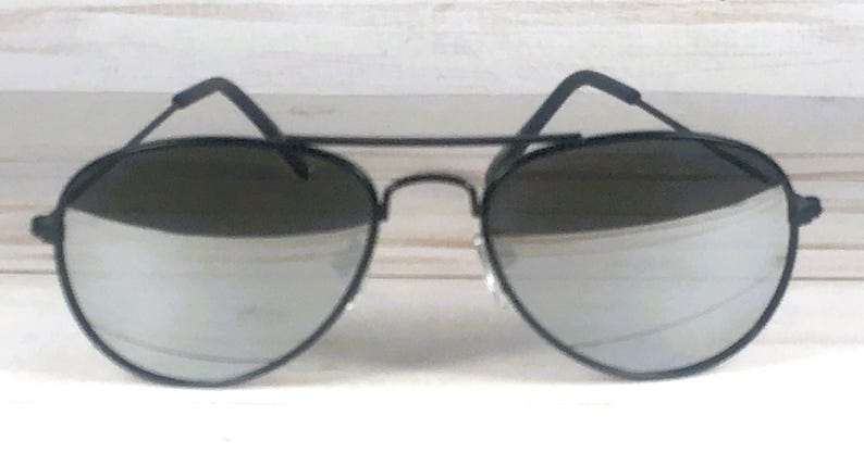 May include: Aviator sunglasses featuring a thin matte black metal frame with a double bridge design. The lenses are highly reflective and silver in color, providing a mirror-like finish. The temples are thin and black with curved ear pieces.