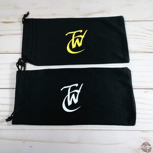May include: Two black drawstring pouches with a white "FW" logo. The top pouch has a yellow logo and the bottom pouch has a white logo.