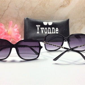 May include: Black sunglasses with a silver chain detail on the arms. The sunglasses are in a case with the word "Yvonne" printed on it.